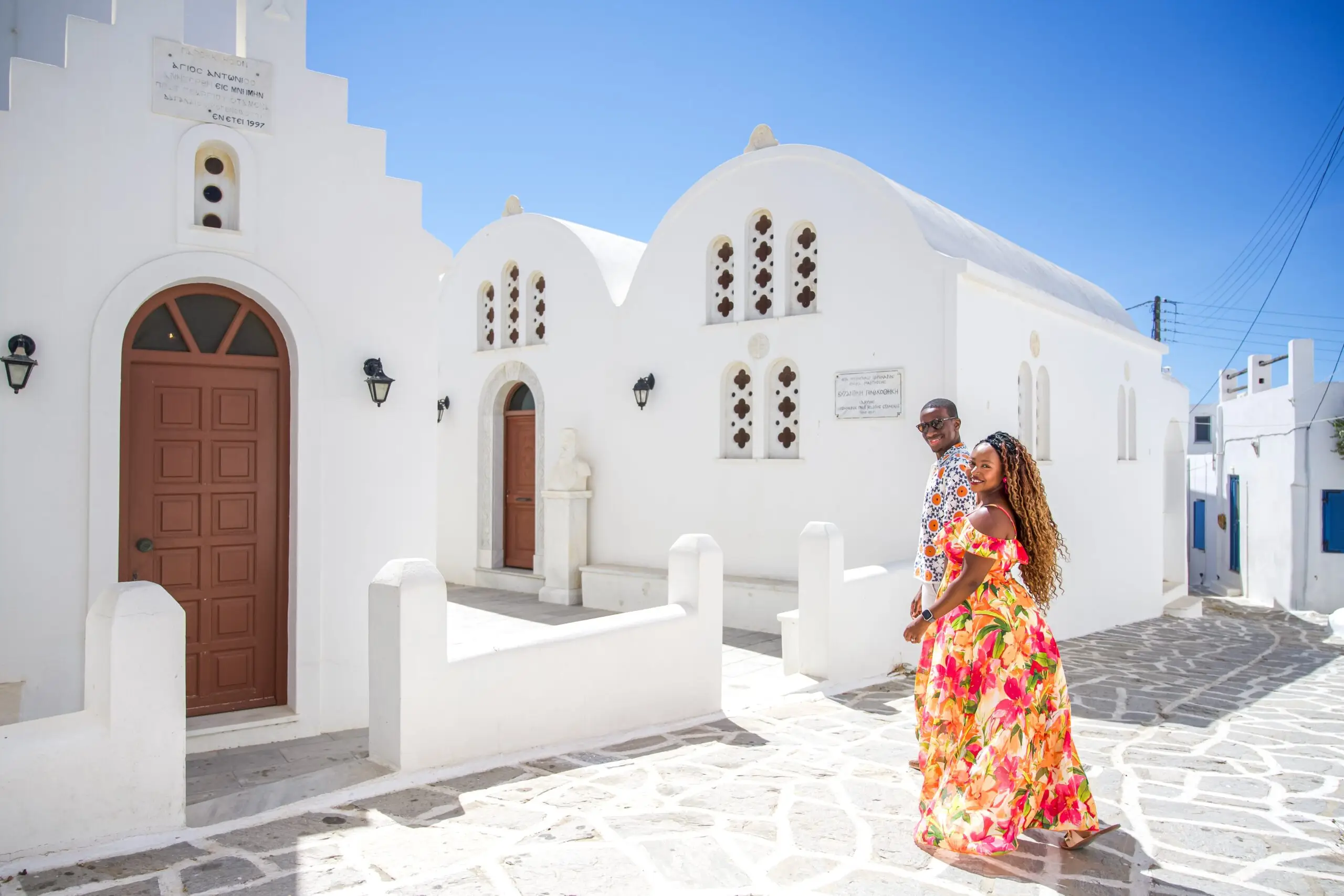 destination-engagement-photography-greece-couple-walking-near-white-church-in-paros