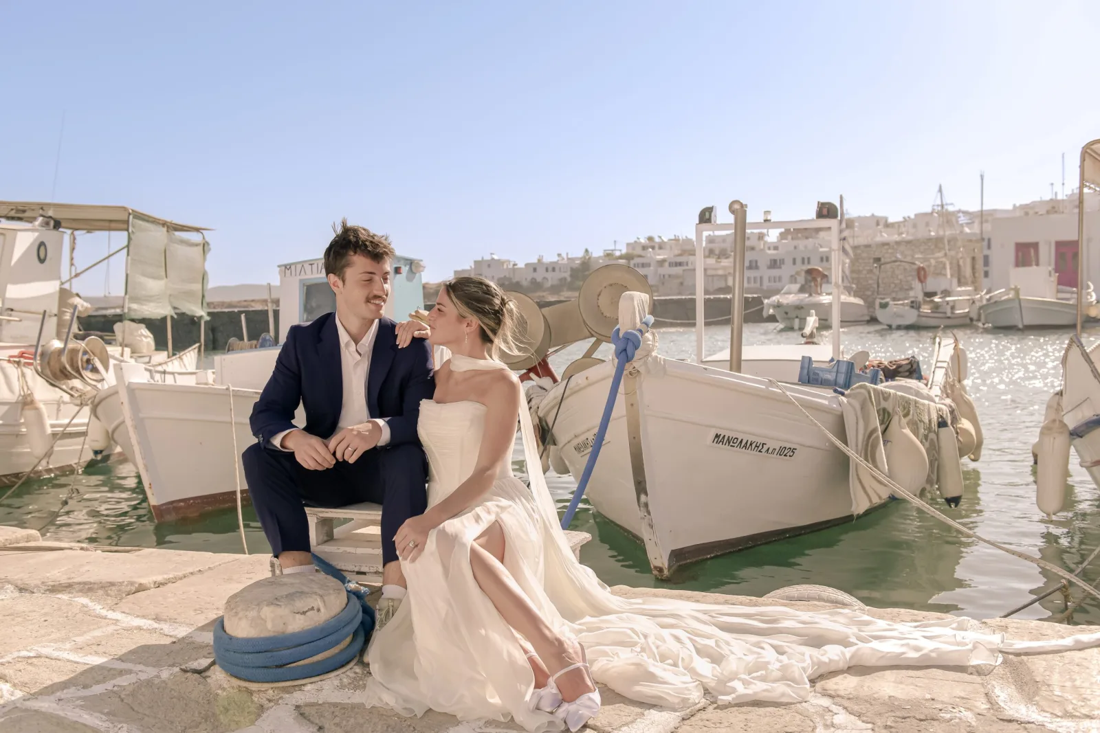 destination-engagement-photography-greece-couple-sitting-by-fishing-boats-in-cycladic-harbor